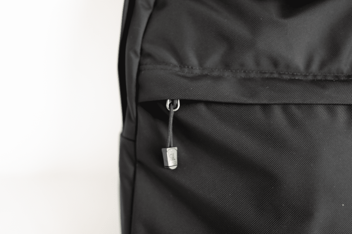 The zipper pull tab peeks out of the hidden pocket on the TOM BIHN Paragon Backpack.